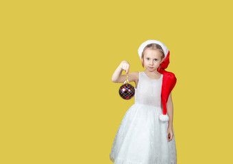 Adorable caucasian girl with a Christmas toy in hand looking at the camera.