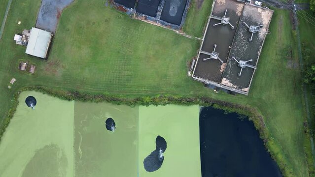 Sewer treatment facility and pump station next to a wastewater stabilization pond. High drone view