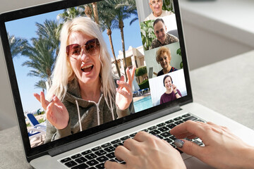 Back view of female employee engaged in team Webcam conference on laptop, have online briefing or consultation from home, woman worker speak talk on group video call with diverse colleagues.
