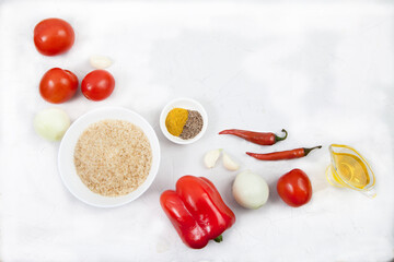 Rice, vegetables and spices for cooking jollof rice on a white background. Copy spaes.