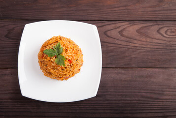 Vegetarian jollof rice with soy meaton a white plate on a wooden brown background.