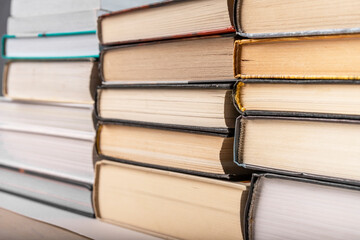 Hardback books stack at bookshelf. Education, preparing for exams, dissertation writing, reading...