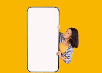 Cheerful asian lady showing big white empty smartphone screen