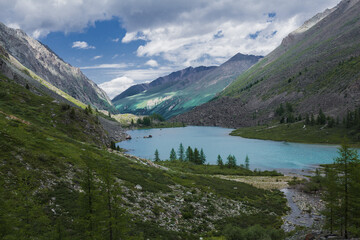 Naklejka na ściany i meble A mountain lake among hills covered with forest and rocks
