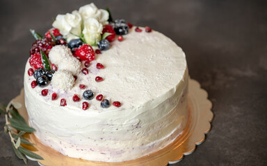 white cake with berries and flowers on a dark background