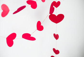 red and pink  hearts on red threads on a white background