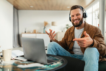 Guy Video Calling Using Laptop Wearing Earphones Communicating Online Indoor