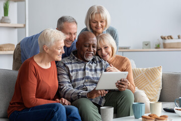 Happy elderly people spending time together at home, using gadgets