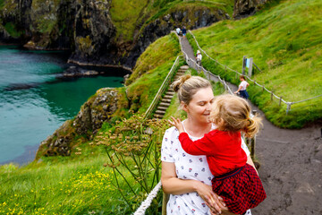 Toddler girl and mother on Carrick-a-Rede Rope Bridge, famous rope bridge near Ballintoy, Northern...