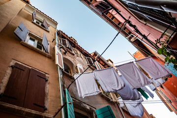Fototapeta na wymiar Narrow Alley With Old Houses And Freshly Washed Laundry In The City Of Rovinj In Croatia