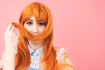 stylish caucasian costume player teenager playing with her ginger hair making moustache - pink background. High quality photo