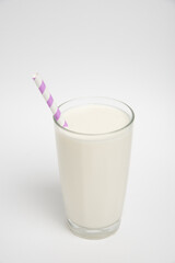 Milk glass with colored straw close-up on a white background