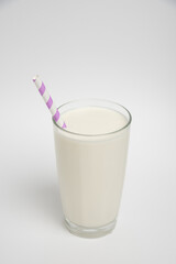 Milk glass with colored straw close-up on a white background