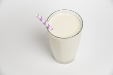 Top view. Milk glass with colored straw close-up on a white background