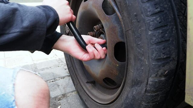 Car wheel replacement. The key unscrews the front wheel of the car.