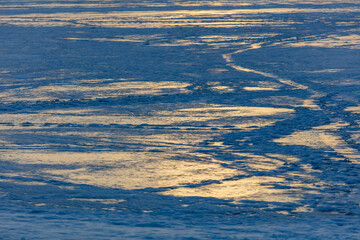 Snow on the lake in winter in the rays of sunset.