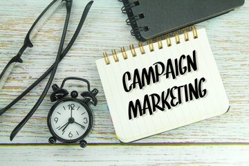 alarm clocks, glasses and notebooks with the word marketing campaign