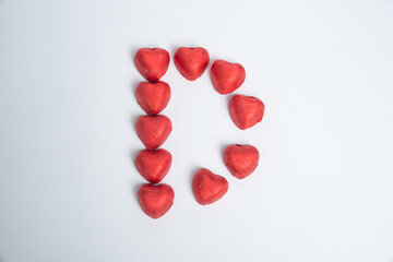 Chocolate red heart sweets in the form of the letter D for Valentine's Day on a white background