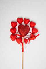Chocolate red heart sweets for Valentine's Day on a white background in the shape of a circle with a heart decoration on a wooden pole in the middle.