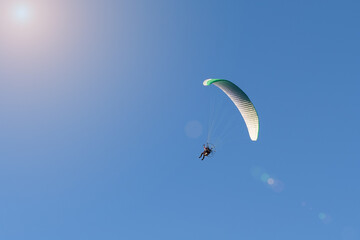 Motorized paraglider flies in the blue sky, extreme sports