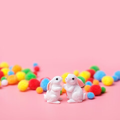 two cute white rabbits and colorful balls on abstract pink background. Easter bunnies toys. minimal composition, creative concept. Copy space