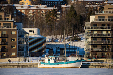 Naklejka premium Sundsvall, Sweden A residential apartment building in the Sundsvall harbour and a boat in the ice.