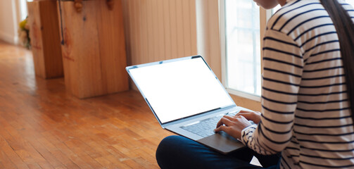 Obraz premium Woman sitting on living room floor using laptop with blank screen for copy space.