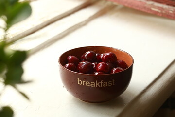 Bowl of ripe sweet cherries on the windowsill.