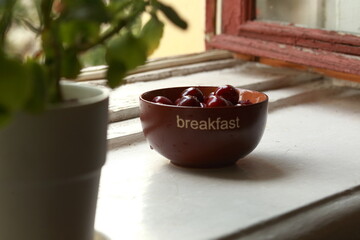 Bowl of ripe sweet cherries on the windowsill.