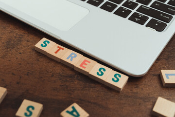 Stress word written on wooden letter cubes tiles - computer desk and keyboard. High quality photo