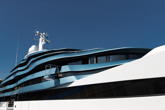 Bottom view of decks of huge yacht of blue color at sunny day, glossy board of the motor boat, sun reflection on glossy board, blue sky is on background