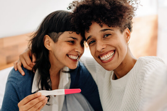 Female couple taking a selfie with their positive pregnancy test