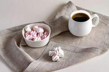 Hot fragrant coffee and sweet marshmallow in a white bowl on a linen serving napkin