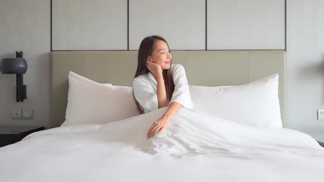 A pretty young woman sitting up in bed enjoying the morning.