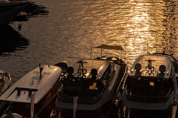 Top decks of luxury motor boats with sun reflections in port of Monaco at sunrise, glossy board,...