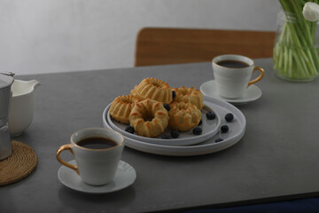Mini bundt cakes with fruits on plate, two cups of coffee on a table. Breakfast