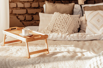 wooden table with a cup Empty Bed, Elegant Brick Wall on Background. Bedroom Modern and Cozy Interior. Soft Pillow and Blanket, Stylish Comfortable Furniture
