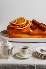 Gigantic orange and cinnamon pound cake on a plate on a table with tiny dishware