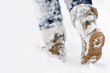 Steps along the snow-covered path. A Human walks in the park in the winter. Place for text,...