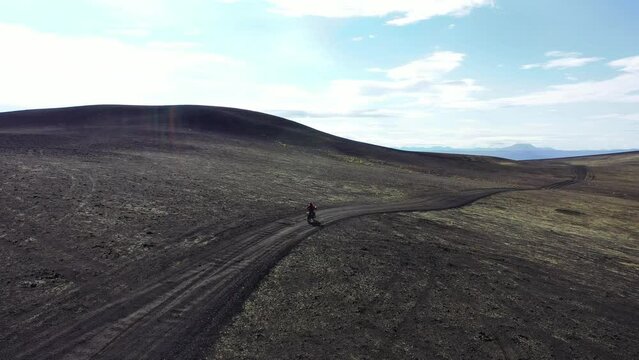 Motorcyclist driving on the road Road across big moss field in area of the Kamchatka volcano  Tolbachik, drone view