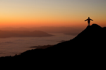 Young backpacker with looking and enjoying sunrise on top of mountain. She strong confidence woman open arms under the sunrise. She enjoyed traveling and was successful when he reached the summit.