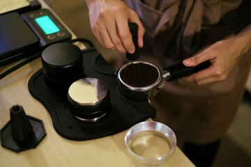 Fototapeta na wymiar Professional barista prepare grinded coffee into portafilter for espresso brewing process