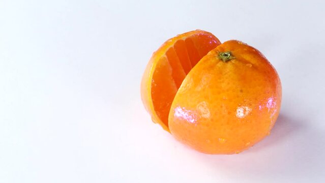 Very sharp knife cutting a thic slice of tangerine in white surface. Chopping, slicing. Close up.