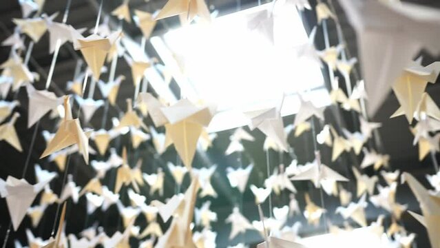 Paper cranes hanging from a ceiling with a skylight