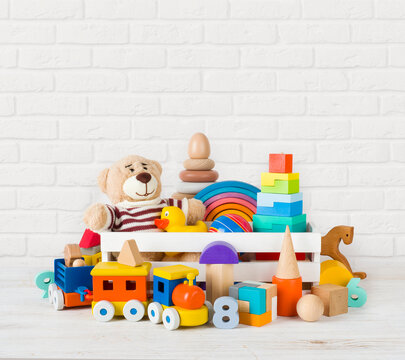Set of different children toys on wooden table near wall