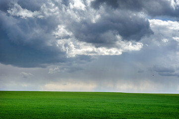 Beautiful storm clouds over green spring field