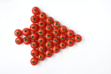 Red tomatoes are stacked on a white table in the form of an arrow 