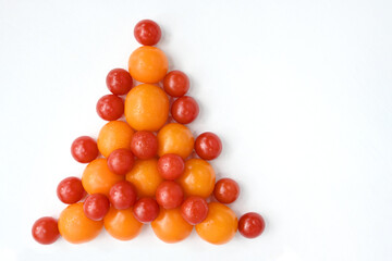 Red and yellow tomatoes stacked on a white table in the form of a Christmas tree