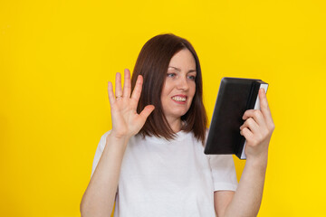 Fototapeta premium Video chat with friend via tablet isolated on yellow background