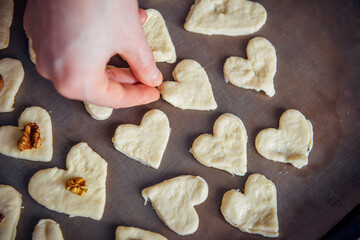 Raw homemade heart-shaped cookies on a baking sheet. Concept of fresh pastry, surprise for Valentine's day.